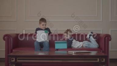两个穿着同一件衣服的<strong>兄弟</strong>在家沙发上用小玩意。 小<strong>兄弟</strong>在沙发上看着一台平板电脑。