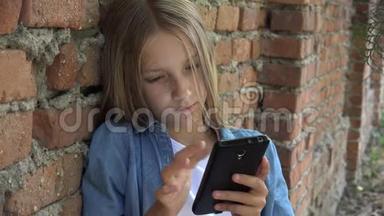 孩子使用智能手机，孩子玩智能手机，女孩在公园户外