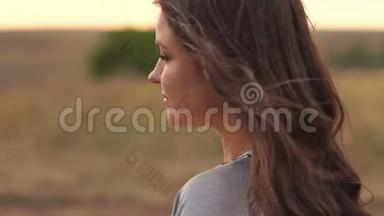 一个年轻女孩的肖像，长发在夕阳下的一片田野里，在<strong>大风</strong>中。