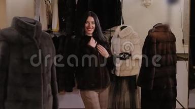 一个留着长发的豪华女孩在一家女服装店试穿`一件毛皮大衣。