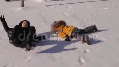 一家人躺在雪地里做雪天使。 母亲和孩子躺在雪地上。