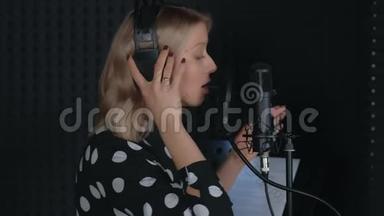 女歌手戴耳机唱歌，麦克风录音歌曲在录音室。