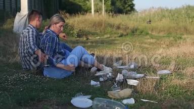 不负责任的青少年坐在公园里的垃圾中，他们喝饮料。