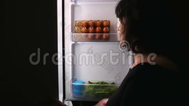女人在夜里，打开冰箱，拿蛋糕，关上冰箱。