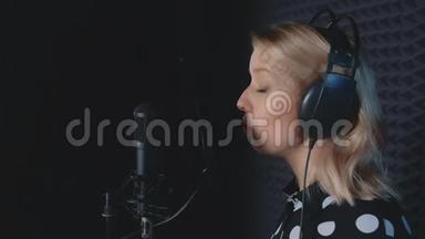 女歌手戴耳机唱歌，麦克风录音歌曲在录音室。