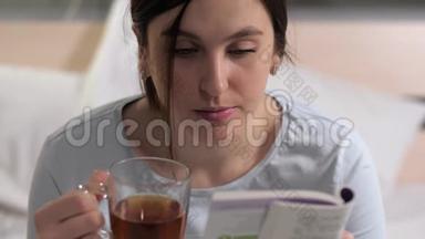 女孩在<strong>看书</strong>。 年轻迷人的白种人女人晚<strong>上</strong>坐在<strong>床上看书</strong>，喝红茶