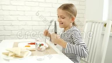 儿童在厨房吃早餐，儿童吃煎蛋，少女享受蔬菜，绿色健康食品