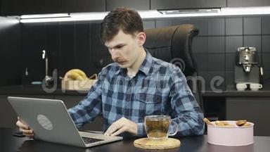 白种人在家里用笔记本电脑。 商人开始在厨房使用笔记本电脑。 快乐男自由职业者在线工作