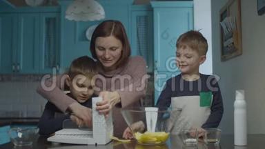 家庭烹饪薯片在切片机上。 母亲和儿子们做土豆片，把它放进玻璃碗里。 幸福的家庭