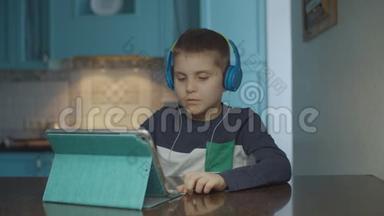自闭症男孩在厨房里用带耳机的平板电脑。 有自闭症的孩子在家里四处张望。 自闭症