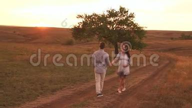 幸福的孕妇和她的丈夫在日落时沿着乡间<strong>小路散步</strong>