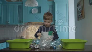 金发学龄前男孩<strong>分拣</strong>家庭<strong>垃圾</strong>，以回收塑料和锡。 环保家庭减少塑料