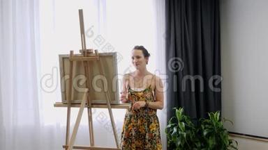 年轻有才华的女人在艺术之家画画布。 女艺术家站在画架附近，画在画布上。 <strong>内部资料</strong>