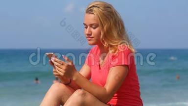 年轻漂亮的女孩在大海的背景上读短信
