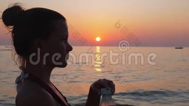 女孩在日落时在<strong>海边</strong>或<strong>海边</strong>喝水。