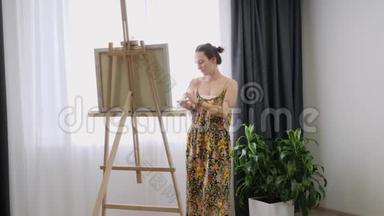 艺术家妇女站在画架上，在画室里用丙烯酸颜料画画布