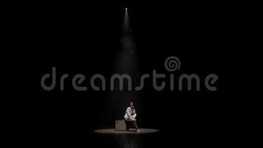 一个女人在黑暗中在白色聚光灯下上台的肖像。