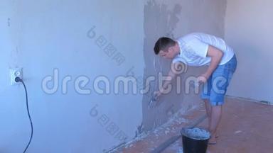 石膏工人正在用长金属工具刮刀将湿石膏对准墙壁。