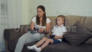 母子俩在家玩电子游戏一<strong>起坐</strong>在沙发上..