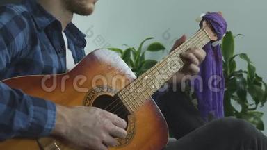 有胡子的年轻音乐家在家里坐在床上练习现场<strong>音乐会</strong>，演奏吉他<strong>独奏</strong>。