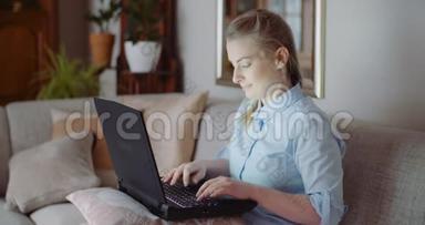 微笑的女人在家里的办公室用笔记本电脑工作。 女商人在电脑键盘上打字。