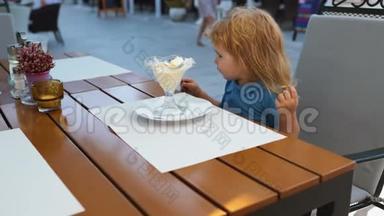 幼儿童年儿童幸福观念.. 可爱的学步男孩吃冰淇淋。 咖啡馆的冰淇淋