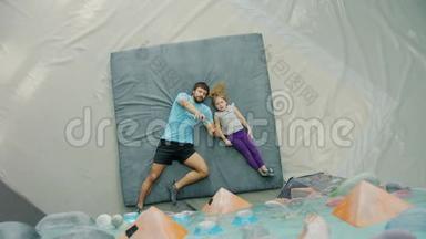 父亲和女儿躺在攀岩场的垫子上谈论攀岩