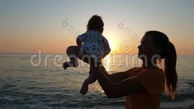 母亲抱着婴儿，看着海边或海边的日落。