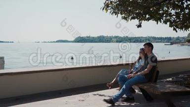 情侣坐在长廊树下的长凳上，欣赏加德纳湖的景色