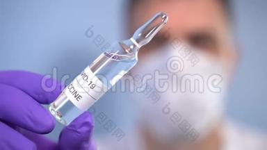 冠状病毒疫苗。 一位戴着防护手套和面罩的生物学家手里拿着一个安瓿，里面有一种COVID-19的药