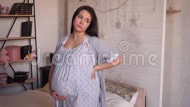 在卧室里有胃痛或背痛的悲伤<strong>孕妇</strong>穿着<strong>睡衣</strong>。