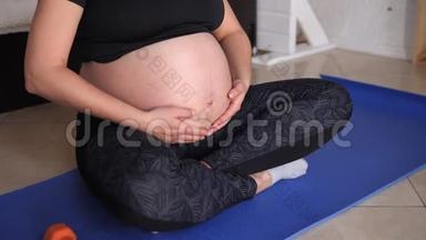孕妇在家做运动的特写，她<strong>轻轻地</strong>抚摸着她的胃。