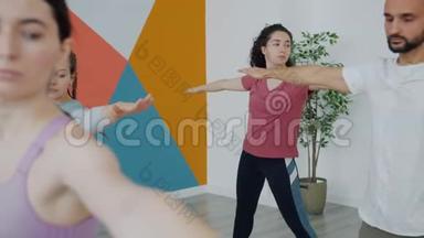健康的年轻人在室内运动俱乐部练习瑜伽，弯曲身体，举起手臂