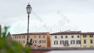 女人坐在路灯附近的栅栏上，享受<strong>意大利</strong>冰淇淋。 总计划。 <strong>彩色房子</strong>在背景上