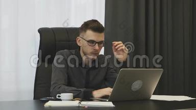商人看着笔记本电脑屏幕，摘下眼镜。 <strong>年轻人</strong>忙碌了一天后<strong>累了</strong>。 男人用手摸着头