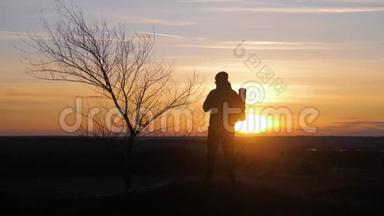剪影孤独的人，背着背包在山里，在夕阳和夕阳下散步。 旅游概念