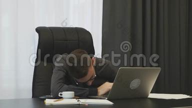 年轻的经理工作过度劳累. 男员工在办公室忙碌了一天后累了。 商人摘下眼镜和擦布