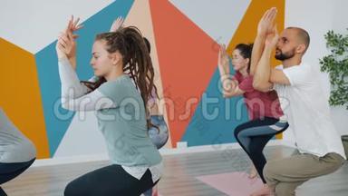 在现代体育中心的瑜伽课上，女生和男生都在练习鹰的姿势