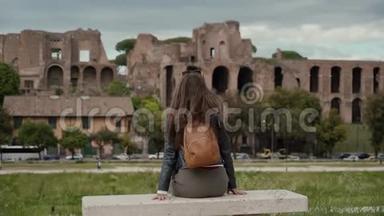 意大利罗马阳光明媚的一天，快乐的女游客坐在石凳上俯瞰马戏团的古老遗址