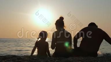 父母带着孩子在海边或海边享受日落。