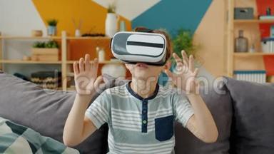快乐男孩正在用虚拟现实眼镜看着周围坐在公寓里打手势