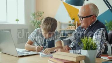 快乐的孩子和爷爷一起做家庭作业，高举大拇指