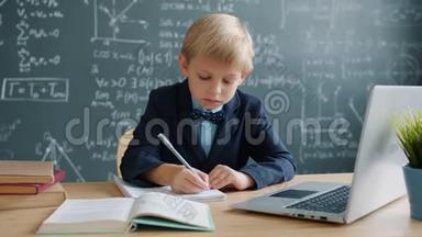 在学校学习科学的年轻天才在笔记本上认真地写字