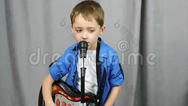 一个小男孩拿着吉他。 幼儿对着话筒唱歌.. 幼儿播放和学习音乐..