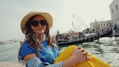 可爱的女孩戴着太阳镜，帽子坐在码头上，和游客一起看着贡多拉斯