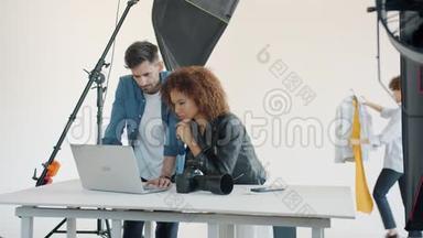 模特和摄影师使用笔记本电脑在演播室交谈，享受商务交流
