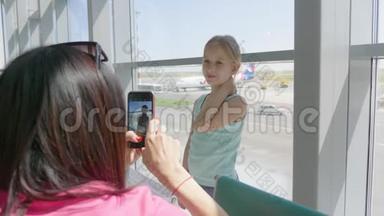 年轻的母亲<strong>在机场</strong>等他们的航班时<strong>在</strong>电话上拍了一张女儿的照片。 <strong>在</strong>国外旅行