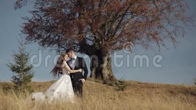 新婚夫妇。 白人新郎和新娘靠近美丽的秋树。 新婚夫妇