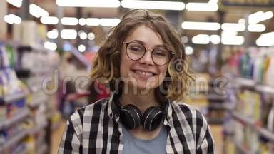 肖像年轻女子站在镜头前，微笑着在超市感受快乐的女孩购物脸<strong>零售店</strong>