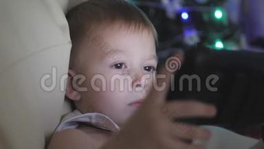 快乐的小男孩玩，看看平板电脑附近的圣诞<strong>树</strong>在内部的家。 <strong>夜晚</strong>的圣诞节。